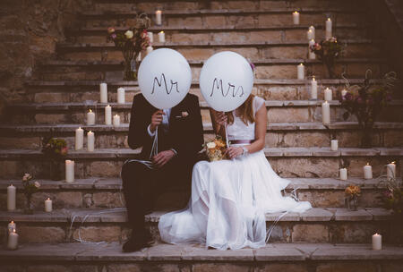 Bride and groom sitting together on rustic staircase and holding balloons