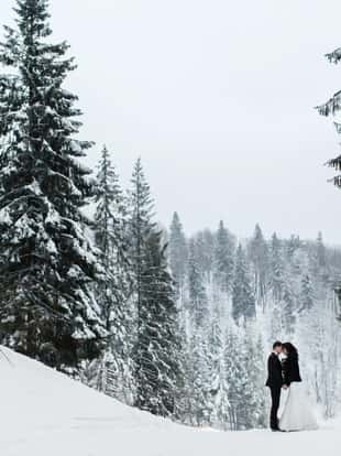 Just married couple kissing, mountains landscape in snow on the background.Lovers in ski resort