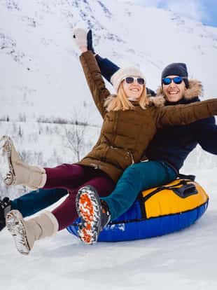 Happy people on tube outdoors in mountains in winter snow. Concept of Christmas holidays