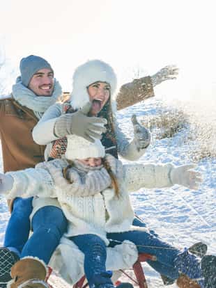 Familie rodelt auf dem Schlitten durch den Schnee im Winter und hat Spaß