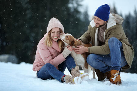 Cute couple with dog near forest. Winter vacation