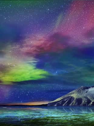 Gorgeous, unreal beautiful night view of the reflection of the northern lights in the water of the ocean and snow-capped mountains. Night Northern Lights is just an amazing sight.