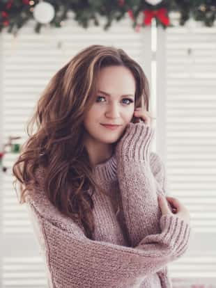 Cheerful beautiful young woman sweater in decorated Christmas room