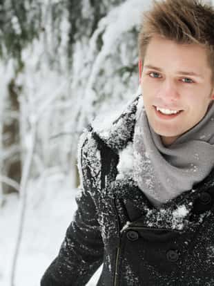 handsome smiling young man posing in winter park