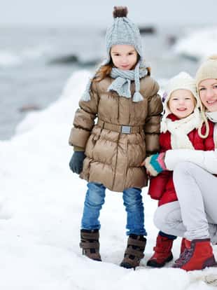 Young mother and her two daughters by the sea on winter