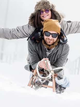 Beautiful couple with sled in snow