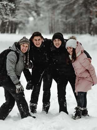 Happy friends in winterwear playing with snow in park. Ukraine 2019