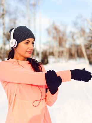 Girl athlete does stretching before training in the snow in the winter.
