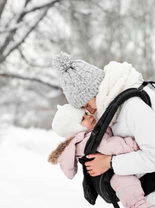 Little baby girl and her mother walking outside in winter Mother is holding her baby babywearing the ergo carrier
