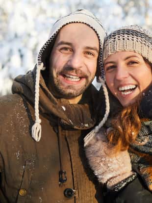 Waist up portrait of happy adult couple having fun in winter forest  and smiling, copy space