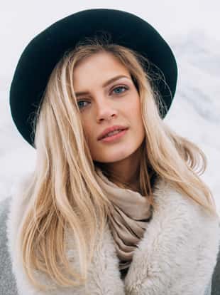 Portrait of beautiful smiling blonde woman in hat and grey coat