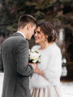 Winter fairy tale. The bride and groom stand in the winter park, huddled together