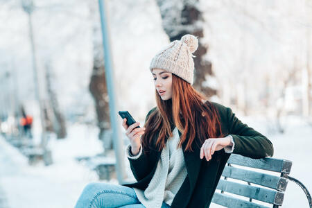 Young  woman smiling with smart phone and winter landscape