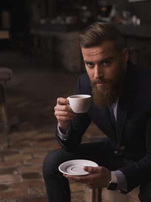 Portrait of cheerful young man drinking a cup of tea in an old cafeteria.