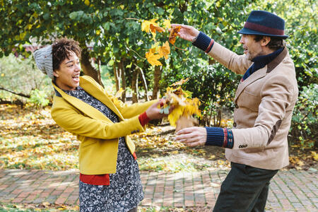 Autumn, an engaged couple of different ages, a man and a woman, launches into the air the yellow leaves