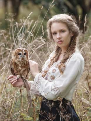Beautiful romantic woman with an owl. The bird sits on her hand