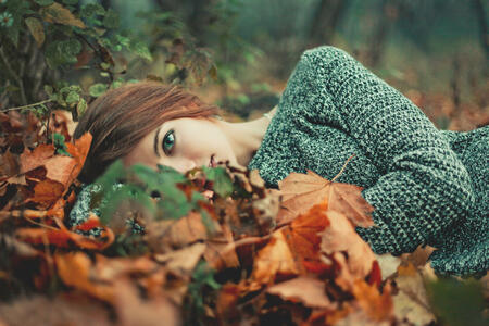 Portrait of beautiful girl with blue eyes. Lay on the ground in the forest