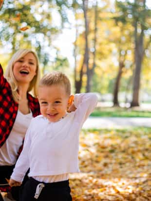 Mother and her son are having fun and trowing leaves up in the air