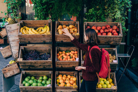 Young Caucasian woman choosing fresh fruits on the street of Florence