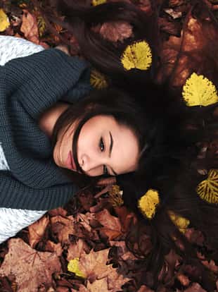 Portrait of beautiful young woman laying on leaves