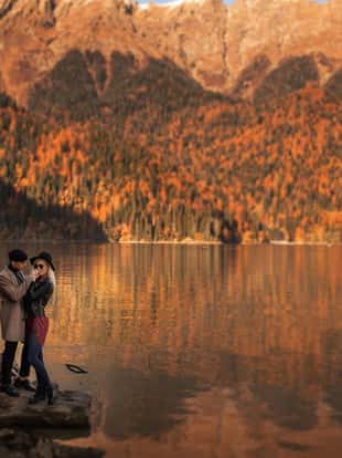 A couple of lovers man and woman stand near the lake between the mountains.