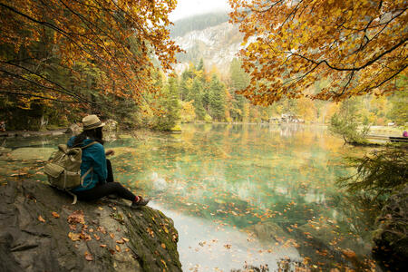 Asian woman  enjoying the view of turquoise lake Blausee in Swiss Alps