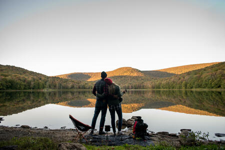 A couple that has hiked to a lake in the mountain side to camp and relax.