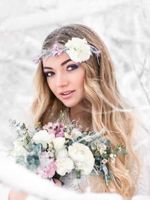 Winter bride in a snowy forest in the open air with beautiful flowers on her head and a bouquet. The concept of a winter wedding. Soft focus and blur effect.