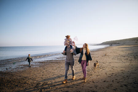Three generation family enjoying walking along the coast. Its cold outside so they are wrapped up warm.