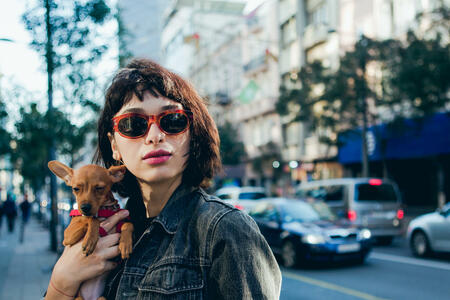 Girl walking on the street and holding her puppy Miniature Pinscher