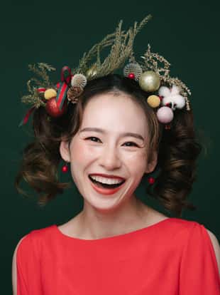 Portrait of young woman with pine branches and Christmas decorations on her hair