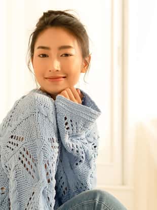 Portrait of beautiful young Asian woman smilling friendly and looking at camera in living room at home on a bright winter morning. Concept woman lifestyle and winter. Autumn, winter season.