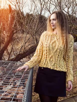 Woman in a handmade yellow knitted sweater posing on a morning walk by the lake