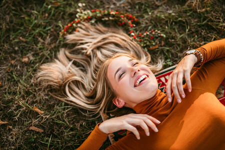 Pretty blonde smile woman lying down in grass enjoys sunset at picnic