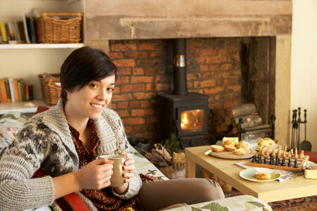 Young woman having tea by fire smiling at camera