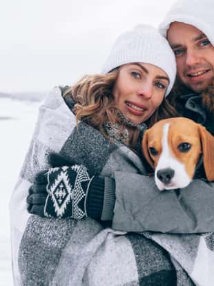 Happy couple with a dog at the winter landscape