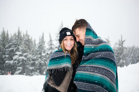 Real lifestyle portraits of a cute young couple together in love during the winter season in the mountains. This is from an engagement shoot in the snow in 2015.
