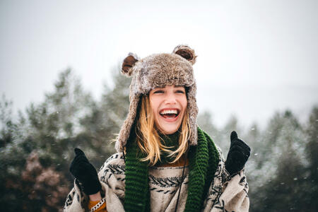 Outdoor close up portrait of young beautiful happy smiling hipster girl, wearing stylish poncho and fake fur hat.