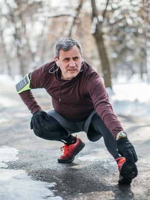 One man, senior adult guy preparing for jogging outdoors in park, on a cold winter day alone.