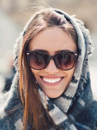 Young woman wrapped in scarf smiling to the camera