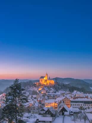 Elevated view over the beautiful village of Gößweinstein with it´s landmark Basilica and Burg Gössweinstein in the distance on a beautiful winter day at dusk.