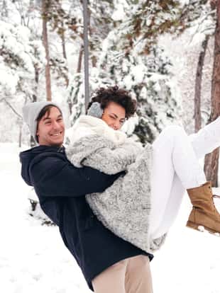 Young man is holding his girlfriend aloft in the snow