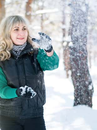 Adult woman plays snowballs in winter forest. Freedom and joyful concept.