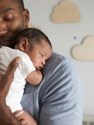 Father Holding Newborn Baby Son In Nursery