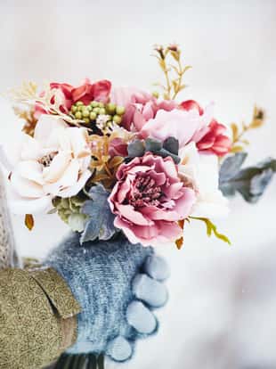 Female hands holding beautiful flower bouquet in snowy weather