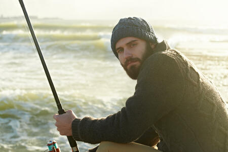 Cropped shot of a bearded man fishing on the beach
