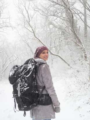 Hiker woman at the snowy mountain. She has large mountain backpack.