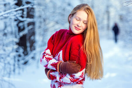 Beautiful young woman with long blond hair posing in a winter forest