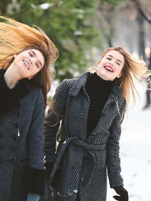 Two young Caucasian beautiful women in the snow having fun.