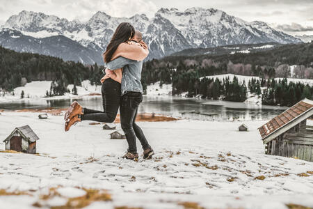 Photo of young romantic couple standing and hugging over  the beautiful scenery of mount cook in Bavarian Alps,. The rocky shore, stunning snow mountain and the clear sky create a perfect background or wallpaper. Couple traveler enjoining Beautiful Gerald Lake with snow capped in the morning sunrise at German. Landmark and popular for tourist attractions. travel concept